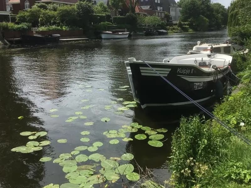 Case affacciate su un canale con barche ormeggiate e ninfee sull’acqua