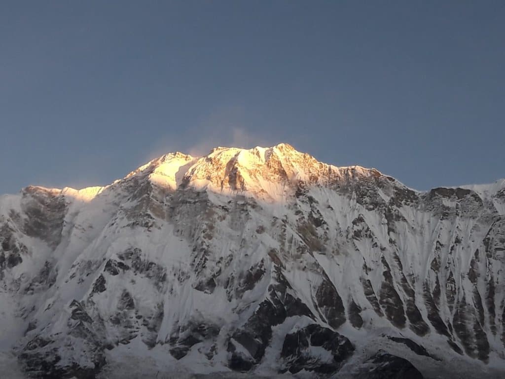 Una vetta innevata illuminata dalla prima luce, sotto un cielo terso