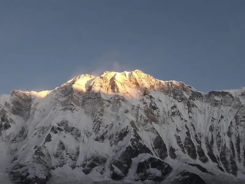 Una vetta innevata illuminata dalla prima luce, sotto un cielo terso